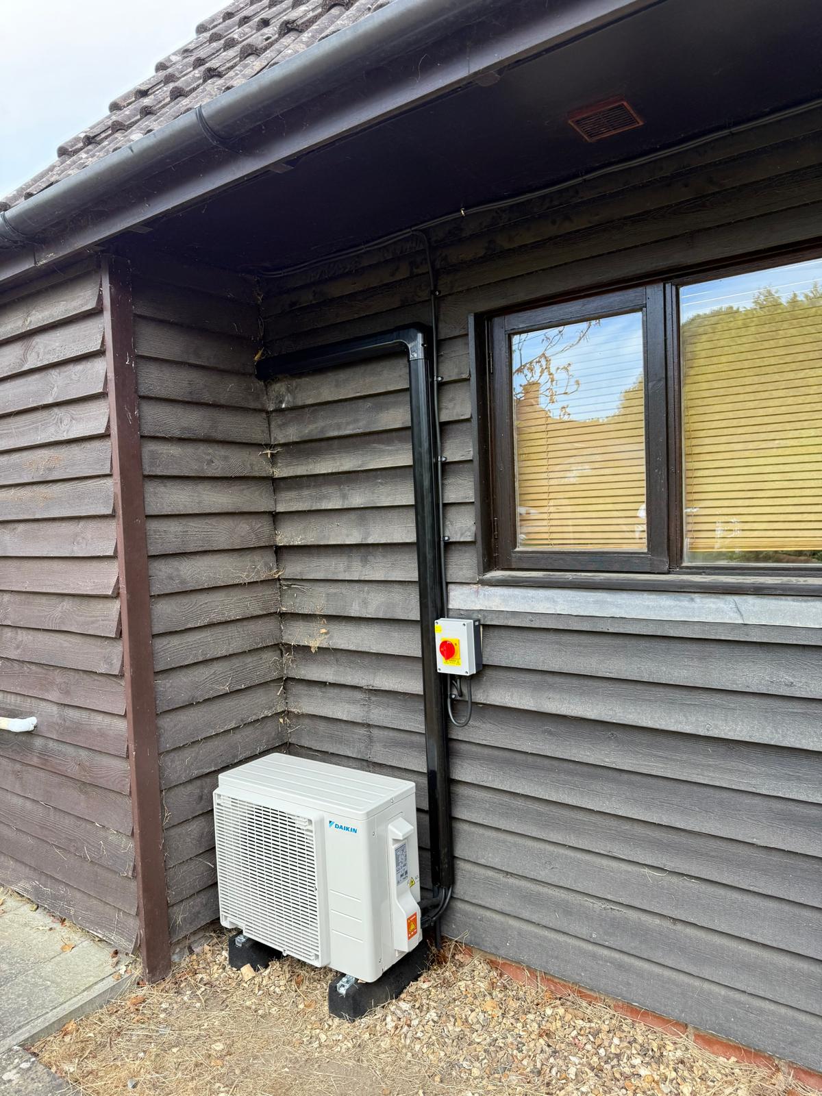 Daikin outdoor air conditioning unit installed beside a wooden clad building